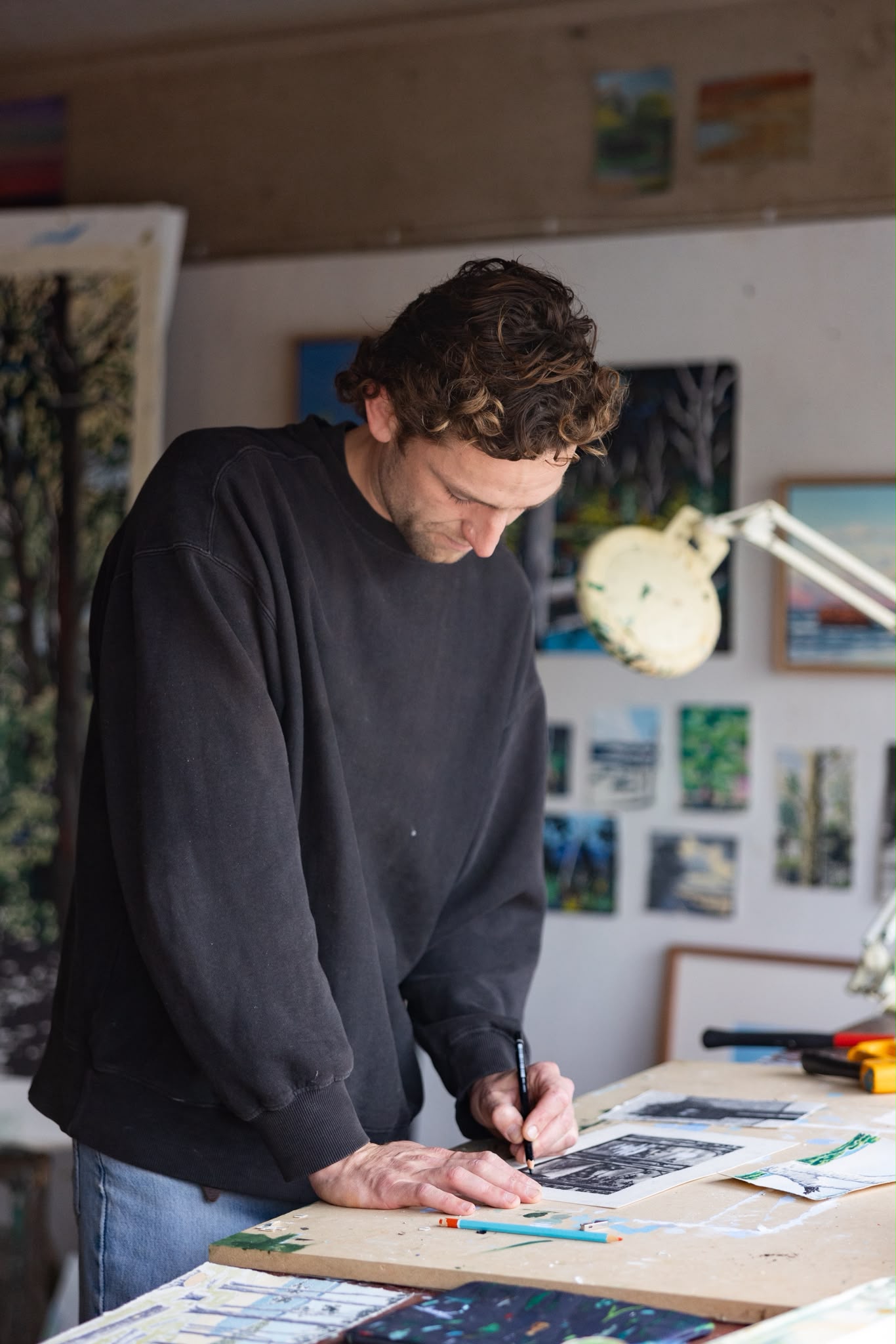 James Mulcahy in his studio, seated beside his dog, surrounded by paintings